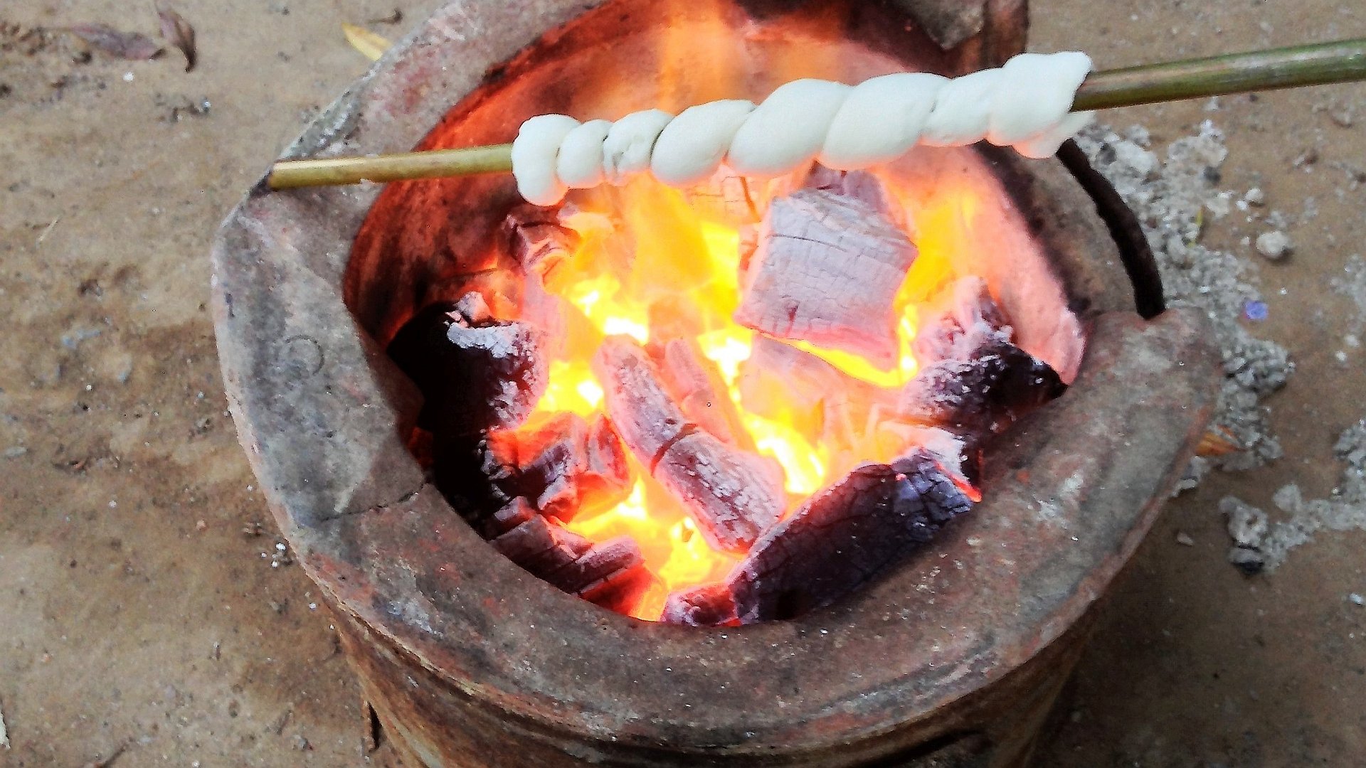 Stockbrot über einer traditionellen thailändischen Feuerstelle