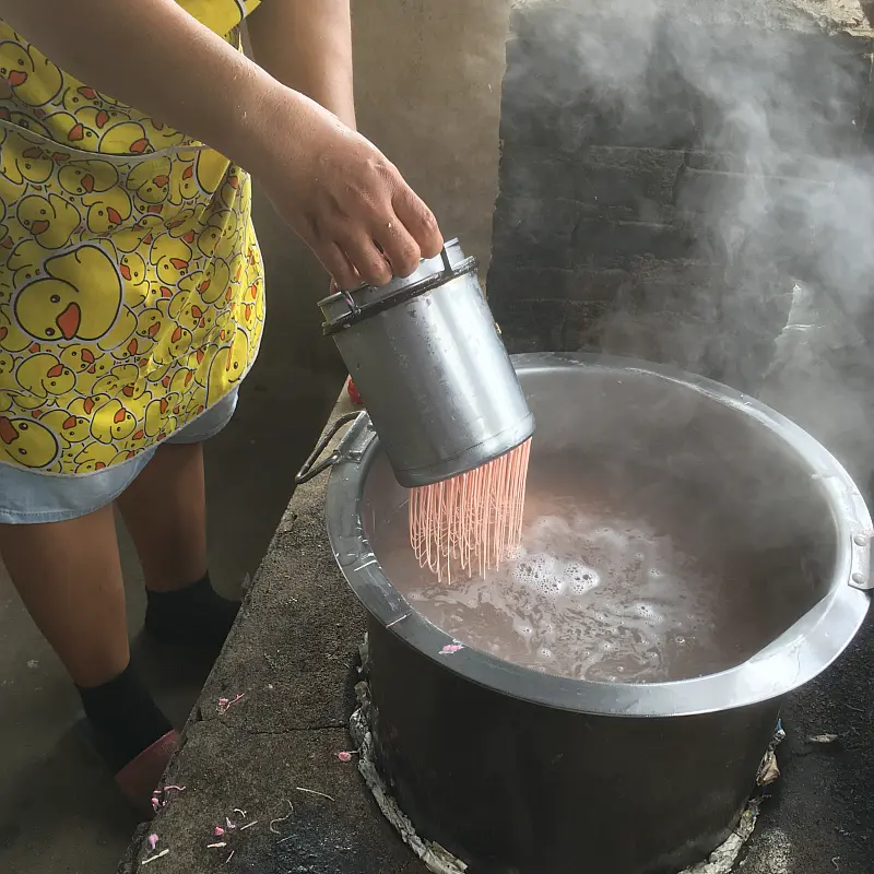 In kochendes Wasser gepresst entsteht die typische Form der dünnen Reisnudeln.